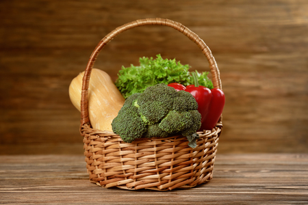Fresh vegetables in wicker basket on wooden backgroundの写真素材