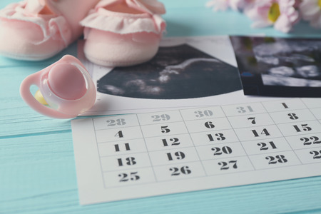 Baby waiting concept. Ultrasound photo and calendar on blue wooden backgroundの写真素材