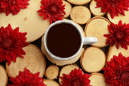 Beautiful composition with cup of coffee and red flowers on wooden backgroundの写真素材