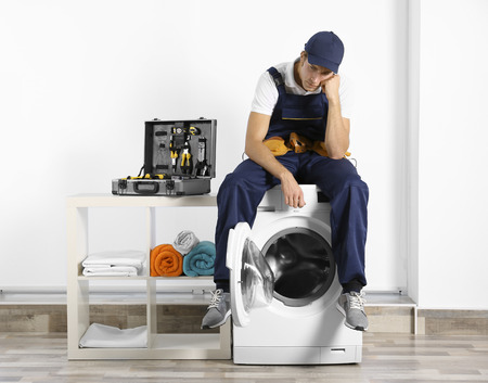 Plumber sitting on washing machineの写真素材