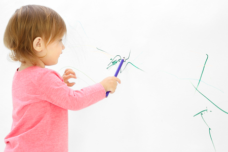 Cute little girl drawing on light wallの写真素材