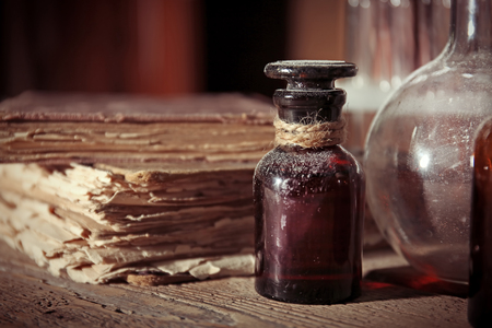 Vintage glass bottle with old books on wooden table, closeupの写真素材