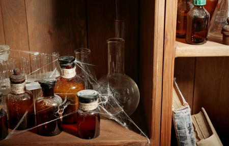 Vintage glass bottles with spiderweb on wooden shelf, closeupの写真素材
