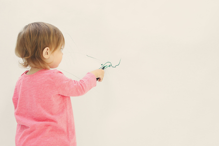 Cute little girl drawing on light wallの写真素材