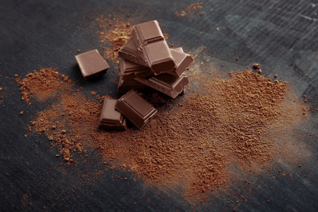 Broken chocolate pieces and cocoa powder on wooden backgroundの写真素材