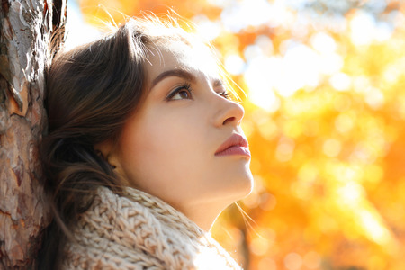 Beautiful young woman near tree in autumn park, close upの写真素材