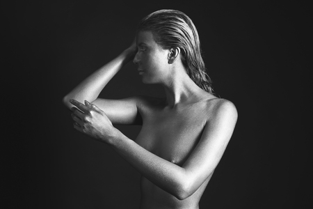 Beautiful woman painted with silver paint on dark backgroundの写真素材