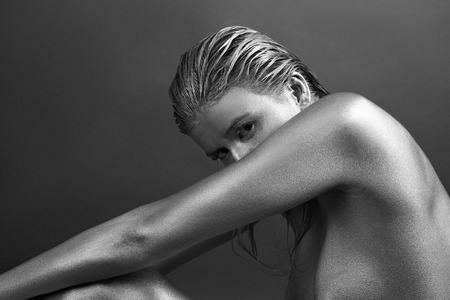 Beautiful woman painted with silver paint on dark backgroundの写真素材