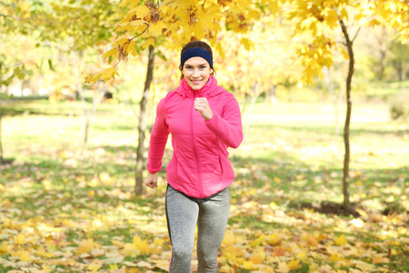 Sporty young woman running in autumn parkの写真素材