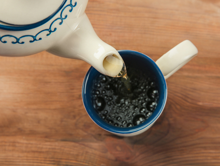 Pouring tea into cup on wooden backgroundの写真素材