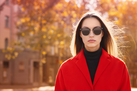 Beautiful young woman wearing sunglasses on autumn dayの写真素材