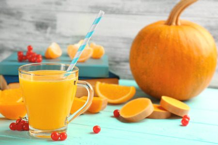 Fresh pumpkin smoothie with oranges and books on tableの写真素材