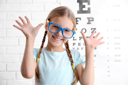 Little girl with spectacles on ophthalmic test chart backgroundの写真素材