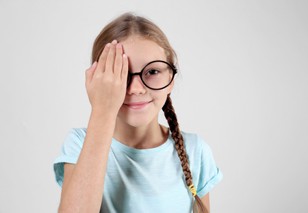 Little girl having eye test, on light backgroundの写真素材
