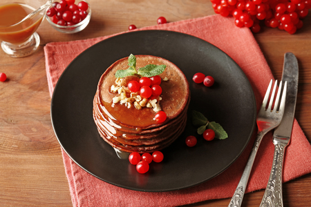 Tasty chocolate pancakes with  viburnum and nuts on black plateの写真素材