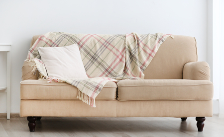 New cozy couch with pillow on light wall backgroundの写真素材