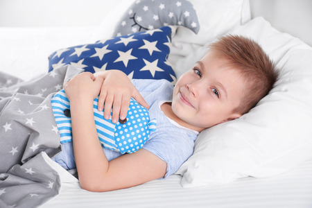 Little boy with toy whale in bedの写真素材