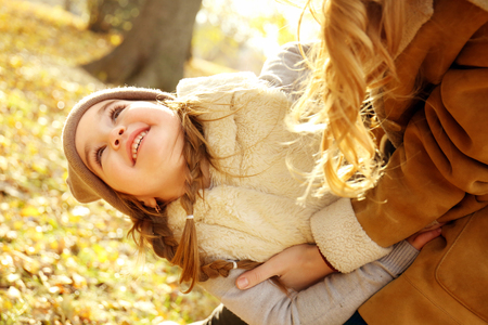 Mother and daughter playing in beautiful autumn parkの写真素材