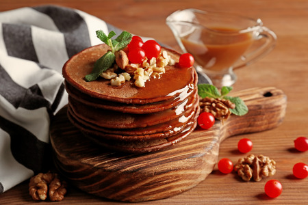 Tasty chocolate pancakes with  viburnum and nuts on wooden board, closeupの写真素材