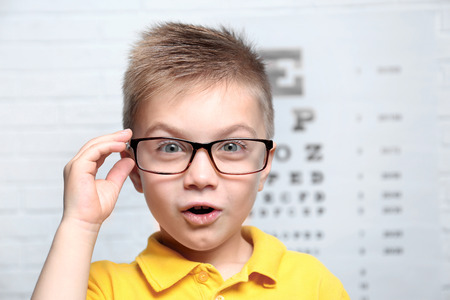 Little boy with spectacles on ophthalmic test chart backgroundの写真素材