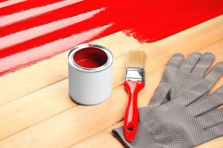 Paint can, gloves and brush on red painted wooden backgroundの写真素材