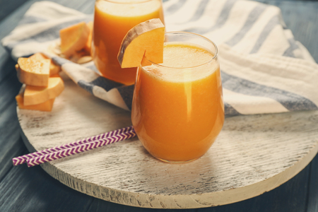 Two glasses with pumpkin smoothie on wooden boardの写真素材