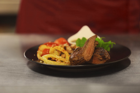 Plate with tasty meat, fried vegetables and sauce on table in restaurant, close upの写真素材