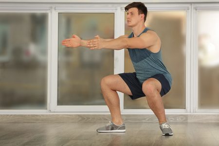 Young handsome sportsman doing exercises indoorsの写真素材