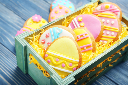 Green box with decorated Easter cookies on wooden backgroundの写真素材