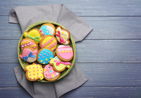 Wicker basket with tasty Easter cookies on grey wooden background