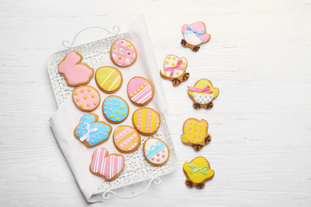 Delicious colourful Easter cookies on tray and white wooden background