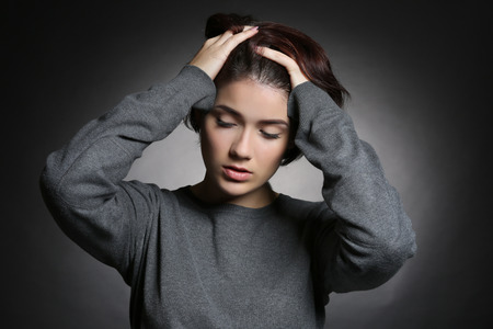 Depressed young woman on grey background