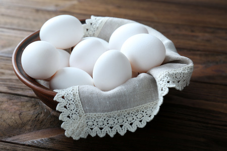 Bowl with raw eggs on wooden backgroundの写真素材