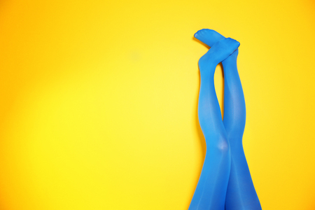 Beautiful woman legs in color tights on yellow backgroundの写真素材
