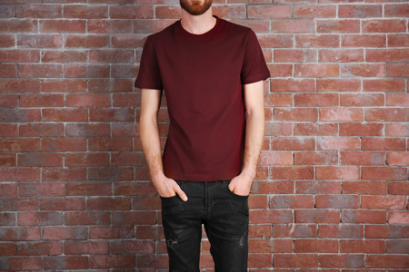 Closeup of man in claret red T-shirt on brick wall backgroundの写真素材