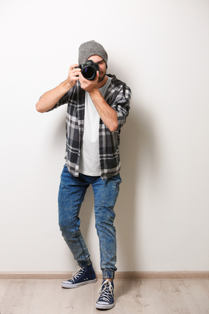 Handsome young photographer on light wall backgroundの写真素材