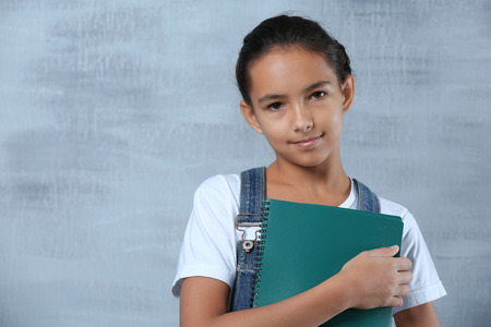 Cute schoolgirl on color background