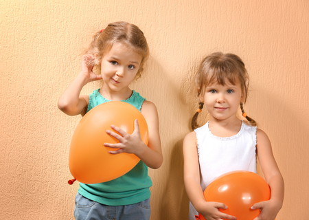 Adorable little girls with balloons on color backgroundの写真素材