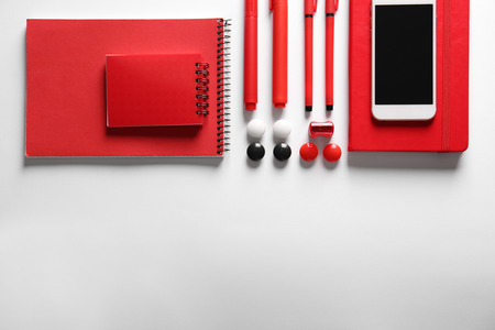 Flat lay composition of red stationery and smartphone on white backgroundの写真素材