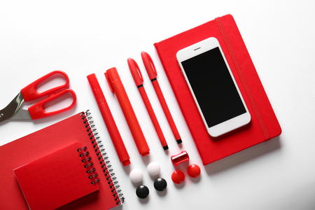 Flat lay composition of red stationery and smartphone on white backgroundの写真素材