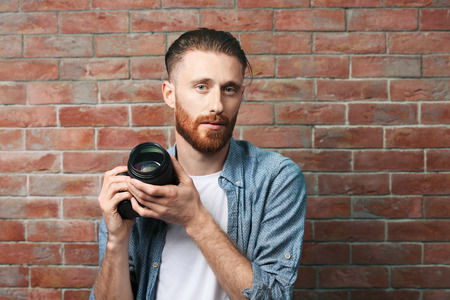 Handsome photographer near brick wallの写真素材