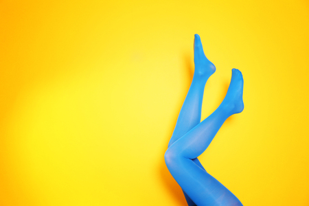 Beautiful woman legs in color tights on yellow backgroundの写真素材
