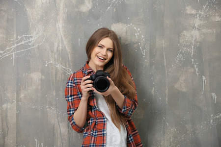Beautiful young photographer near grunge wallの写真素材