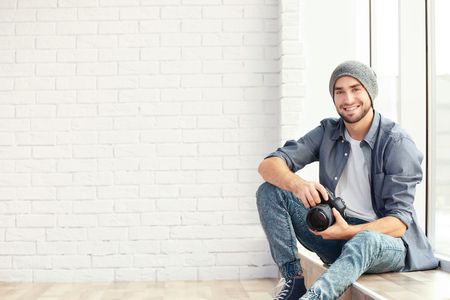 Handsome young photographer sitting on window sillの写真素材