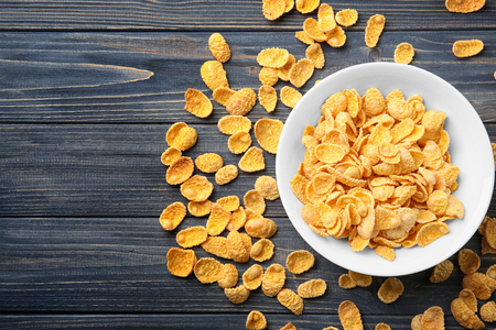 Bowl with cornflakes on grey wooden background