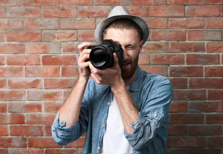 Handsome photographer near brick wallの写真素材