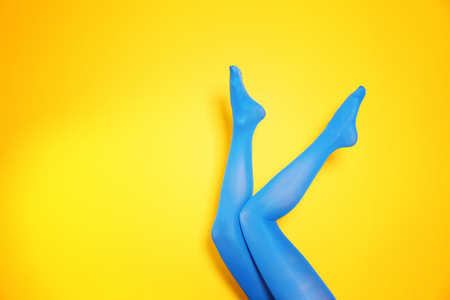 Beautiful woman legs in color tights on yellow background