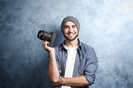 Handsome young photographer near grey textured wall