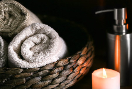 Towels in wicker basket and burning candle, closeupの写真素材