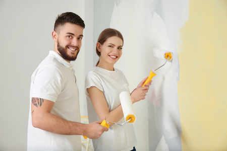 Young decorators painting wall in roomの写真素材
